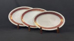 Steatita. Três travessas em porcelana nacional esmaltada, decoração com larga faixa na tonalidade vinho, enriquecida por minuciosos ornamentos geométricos e arabescos, ricamente realçados a ouro, sobre fundo branco. Manufatura no verso. Medindo;28 x 18 cm
