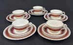 Steatita. Cinco trios para chá em porcelana nacional esmaltada, decoração com larga faixa na tonalidade vinho, enriquecida por minuciosos ornamentos geométricos e arabescos, ricamente realçados a ouro, sobre fundo branco. Composto de 5 xícaras com seus pires e 5 pratos para sobremesa. Uma xícara com fio de cabelo e um prato com bicado.
