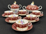 Schmidt. Elegante conjunto para café em porcelana policromada esmaltada sobre fundo branco e vinho, decoração floral com flores e folhagens multicoloridas, enriquecida por delicados ornamentos e frisos em ouro. Composto de: 6 xícaras com os respectivos pires e 2 açucareiros com tampa. Manufatura no verso. Med. do maior açucareiro 12 x 19 cm e 12 x 13 cm.