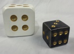 Objeto decorativo. Par de dados ornamentais, fabricado em resina de alta qualidade. Um, em tom branco e outro preto, com as pontuações cavadas em dourado. Medindo: 11 x 11 x 11 cm e 7 x 7 x 7 cm.