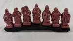 Grupo escultórico, representando os Sete Deuses da Sorte (ou Shichi Fukujin), com seus respectivos nomes gravados, figuras populares da mitologia asiática que representam harmonia e prosperidade. Medindo:9,5x22x3,5cm. 