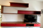 João Pegorim. Importante estante suspensa modular em madeira, composta por amplo módulo inferior com gavetas de frentes laqueadas em vermelho, nichos abertos e prateleiras aéreas assimétricas de forte influência modernista. Peça de desenho arquitetônico. Sistema com excelente capacidade de armazenamento. Med. aprox. 2,76 m comp. x 50 cm prof. (maior profundidade) e 30 cm prof. (menor profundidade). Retirada em Botafogo.