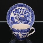 Belíssima xícara para chá inglesa executada em faiança japonesa. Esmaltagem na cor branca, bojo oval com alça lateral em voluta, dotado de rica decoração de tonalidade azul cobalto, padrão willow, aplicada por transferência, composta por paisagem fluvial contendo embarcação, personagens, ponte, pássaros, árvores e pagodes, padrão decorativo replicado no pires. Apresenta manchas do tempo e craquelado característico do envelhecimento do material. Marca da manufatura no verso. Medidas: Xícara: Altura: 5 x Comprimento: 8,5 x Largura: 6 cm; Pires: Diâmetro: 11,5 cm.