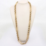 Colar em metal dourado, composto por elos ovais intercalados por módulos vazados em composição geométrica reticulada, executados em relevo torsado e pontilhado. Estrutura articulada em sequência alternada, formando cadeia de elos largos. Acabamento fosco-acetinado. Medida: Comp.: 39 cm.