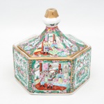 Potiche em porcelana chinesa de formato hexagonal, com tampa facetada e pega superior cônica, decoração policromada em esmaltes da família rosa, apresentando reservas com cenas de personagens em interiores e motivos florais, aves e elementos vegetalistas. Contornos realçados em douração. Marca na base Hand Painted Decoration  Made in China. Apresenta leves desgastes na douração. Medidas: Alt.: 17 x Comp.: 18 x Larg.: 15,5 cm.