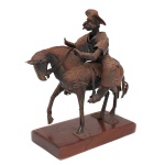 Escultura executada em metal representando Dom Quixote montado em Rocinante, executada em chapas metálicas recortadas, conformadas e soldadas, com pátina oxidada e base retangular em madeira. A composição apresenta o personagem com elmo, barba e armadura, montado sobre cavalo de formas simplificadas. Medidas: Alt.: 30 x Comp.: 26 x Larg.: 11 cm. Apresenta perda da lança.