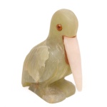 Escultura representando pelicano, executada em alabastro verde, com bico em pedra de tonalidade rosada e olhos aplicados em material sintético. Corpo esculpido em bloco único, com modelagem compacta e definição da plumagem das asas por entalhes incisos e planos facetados, simulando a sobreposição das penas. Medidas: Alt.: 12 x Comp.: 9,5 x Larg.: 5,5 cm.