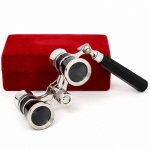 Binóculo de teatro em metal cromado e resina sintética preta, com cabo lateral articulado e regulagem central de foco, acompanhado de estojo revestido em veludo vermelho. Medidas: Comp.: 11 x Larg.: 13 cm(com o cabo).