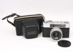 Câmera fotográfica da década de 1960, modelo Yashica Minister III, fabricação japonesa, corpo em metal cromado e revestimento em material sintético texturizado, equipada com objetiva Yashinon 4,5 cm f/2.8, visor óptico frontal e compartimento posterior articulado para inserção de filme. Acompanha tampa de objetiva e estojo de transporte em material plástico moldado com alça. Série nº 8042137. Não foi testada, sem garantias de funcionamento. Estado conforme fotografias. Medidas: Alt.: 9,5 x Comp.: .14 x Larg.:  8cm.