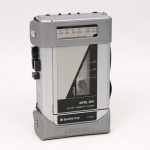 Walkman Sanyo Sportster M-G31A, fabricação japonesa da década de 1980., aparelho portátil para reprodução de fitas cassete, com receptor AM/FM estéreo integrado, gabinete em material sintético, visor frontal de frequências, comandos superiores de operação mecânica e compartimento frontal articulado para inserção de fita magnética. Não foi testado, sem garantias de funcionamento. Estado conforme fotografias. Medidas: Alt.: 16 x Comp.: 10 x Larg.: 4cm.