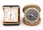 Dois relógios despertadores de viagem da década de 1950/60: a) Marca Silco, fabricação brasileira, mostrador quadrangular com algarismos arábicos, caixa articulada revestida em material sintético, com sistema de apoio retrátil para uso sobre superfície. Medidas Silco: Alt.: 6 x Comp.: 6 x Larg.: 2,5 cm.b) Marca Europa, fabricação alemã, mostrador circular com inscrição 2 Jewels, caixa circular revestida em material sintético texturizado, com mecanismo articulado de abertura para acondicionamento e transporte. Medidas Europa: Diâmetro.: 6 cm. Não estão funcionando, estado conforme fotografias.
