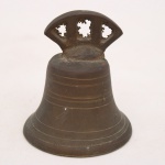 Sino executado em bronze fundido, corpo liso com frisos circulares em relevo e pega superior vazada com ornatos recortados. Interior contendo badalo metálico suspenso por arame. Medidas: Diâmetro.: 8,5 cm.