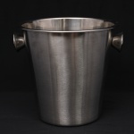 Balde para gelo em aço inoxidável escovado, de formato obconico, com duas alças laterais aplicadas, destinado ao acondicionamento e serviço de bebidas.  Medidas: Alt.: 21 x Diam.: 22 cm.