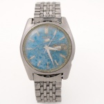 Relógio de pulso Seiko, referência 6109-8029-P, fabricação japonesa, caixa em aço inoxidável com mostrador azul, índices aplicados e calendário duplo com indicação dos dias da semana e datador na posição das 3 horas. Movimento mecânico automático da linha Seiko 5. Fundo de pressão gravado Water Resistant, Stainless Steel e numeração de referência. Bracelete metálico articulado com fecho gravado Seiko. Mostrador possui avaria, visor de acrílico no estado. Não está funcionando, apresenta desgastes e marcas de uso, pulseira necessita ajuste.Medidas: Diâmetro.: 35 mm.