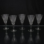 Elegante conjunto de taças de pé alto, para vinho, em cristal diáfano e incolor; bojo obcônico talhado com motivos florais e geométricos, composta por estrelas e painéis facetados, fuste tubular sobre base circular. Composto de cinco(05) unidades. Medidas: Alt.: 15 x Diam.: 8,5 cm.