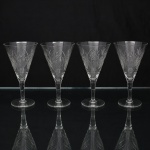 Elegante conjunto de taças de pé alto, para vinho, em cristal diáfano e incolor; bojo obcônico talhado com motivos florais e geométricos, composta por estrelas e painéis facetados, fuste tubular sobre base circular. Composto de quatro(04) unidades. Medidas: Alt.: 15 x Diam.: 18,5 cm.