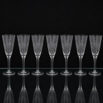Conjunto de flutes em cristal, diáfano e incolor, bojo cônico alongado, lavrado com flores, frutos e composição geométrica, fuste longo sobre base circular. Composto de sete(07) unidades. Medidas: Alt.: 19 x Diam.: 6,5 cm.