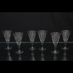 Elegante conjunto de taças de pé alto, para vinho do Porto, em cristal diáfano e incolor; bojo obcônico talhado com motivos florais e geométricos, composta por estrelas e painéis facetados, fuste tubular sobre base circular. Composto de seis(06) unidades. Medidas: Alt.: 10,5 x Diam.: 5,5 cm.
