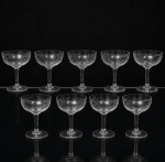Conjunto de taças para champanhe em meio cristal, diáfano e incolor; bojo hemisférico raso, talhado com folhagens estilizadas, fuste tubular sobre base circular. Composto de nove(09) unidades. Medidas: Alt.: 11,5 x Diam.: 9 cm.