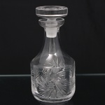Garrafa licoreira em cristal lapidado, diáfano e incolor, corpo de formato bojudo com colo alongado e tampa original ajustada. Decoração executada em lapidação manual com motivos radiais em ponta de diamante e reservas centrais estreladas, distribuídas em repetição ao redor do bojo. Gargalo com acabamento fosco interno para encaixe da tampa. Medidas: Alt.: 22 x Diam.: 10 cm.