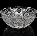 Bowl para centro de mesa executado em cristal prensado, diáfano e incolor; formato hemisférico profundo, com decoração geométrica em relevo composta por sulcos, elementos radiais, losangulares e estrelados, borda recortada e serrilhada. Medidas: Alt. 11 x Diam.: 25 cm.