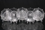 Conjunto de pratos para sobremesa ou serviço de mesa, em vidro prensado. Composto por cinco(05) exemplares de formato circular, com borda recortada e ondulada. Decorados com faixa concêntrica serrilhada em relevo, elemento floral central moldado e gomos radiais distribuídos pelo campo. Medidas: Diam.: 16 cm.