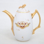 Porcelana Monte Alegre, São Caetano do Sul - SP. Bule para café em porcelana nacional, corpo ovóide sobre base circular, com tampa encaixada e bico vertedor em conformação arqueada. Asa lateral vazada com modelagem angulada. Decoração em esmaltação branca com aplicações em douração brunida no bico, asa, pega da tampa, bordas e elementos ornamentais. Reservas decorativas compostas por cestos florais com arranjos fitomórficos policromos em tons rubro, amarelo e dourado, executados em pintura esmaltada e realces em ouro. Superfície ornada por filetes e motivos curvilíneos esparsos em douração, distribuídos ao longo do bojo. Tampa encimada por elemento fitomórfico estilizado em relevo dourado. Marca da manufatura ao fundo. Medidas: Alt.: 19  x Comp.: 19,5  x Larg.: 11 cm.