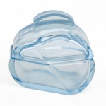 Caixa para conjunto de toucador em vidro prensado, translúcido, de tonalidade azul-claro;  corpo oblongo com cantos facetados e tampa encaixada em perfil arqueado. Composição de linhas escalonadas e frisos concêntricos em relevo, estilo do período Art Déco. Tampa com pega integrada em conformação alçada. Medidas: Alt.: 11 x Comp.: 12 x Larg.: 8,5 cm.