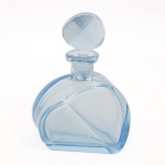 Frasco de perfume em vidro prensado, translúcido, de tonalidade azul-claro; corpo achatado de contorno geométrico com arestas facetadas e decoração em planos diagonais em relevo, estilo do período Art Déco. Gargalo cilíndrico curto com tampa facetada em conformação ovalada, repetindo o desenho angular do corpo. Base plana e composição simétrica de linhas aerodinâmicas. Apresenta quebra na rolha, vide foto. Medidas: Alt.: 17 x Comp.: 12 x Larg.: 9 cm.