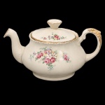 W.H. GRINDLEY, Staffordshire - Inglaterra(Fundada por William Harry Grindley em 1880). Bule para chá em faiança inglesa da década de 1940/50, padrão "Creampetal"; esmaltagem de tom marfim, decoração floral policroma com reservas de rosas e flores campestres distribuídas pelo bojo e na tampa, aplicada por transferência. Borda recortada, bico vertedor ondulado, com acabamento em douradura, repetido na asa lateral em voluta. Marca da manufatura no verso. Medidas: Alt.: 12,5 x Comp.: 23 x Larg.: 15,5 cm.