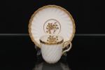 Minton, Staffordshire - Inglaterra. Excepcional xícara para café em porcelana inglesa da década de 1950, padrão Gold Rose. Esmaltagem vítrea de tom branco perolado, realçado por profusa ornamentação com faixas e filetes à ouro, fundo interno contendo flor em reserva. Bojo aproximadamente cilíndrico com alça lateral em voluta, ricamente modelado com frisos em espiral relevados na própria pasta; padrão decorativo replicado no pires. Marca da manufatura no verso. Medidas: Xícara: Altura:  x Comprimento:  x Largura:  cm; Pires: Diâmetro:  cm; Prato: Diâmetro: 17,5 cm. Apresenta marcas de uso e do tempo, vide foto.