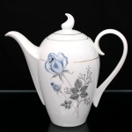 Porcelana Schmidt - Brasil(Fundada em 1945). Bule para café em porcelana nacional, esmaltagem vítrea na cor branca, dotado de rica decoração com padrão de flores em estampagem, predominando as tonalidades azul, cinza e preto, realçado com frisos em douradura; bojo cilíndrico, alongado, de topo arredondado, asa lateral em voluta, bico curvo revirado para fora, tampa ligeiramente abaulada encimada por pega com feitio de chama estilizada. Marca da manufatura ao fundo. Medidas: Alt.: 22 x Comp.: 24 x Larg.: 12,5 cm.