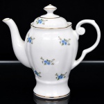 Porcelana Real, Mauá - SP(Fundada em 1943 por Fritz Erwin Schmidt). Bule para café em porcelana nacional da década de 1950/60; esmaltagem vítrea na cor branca, dotada de rica decoração com flores soltas em estampagem policromada, predominando as tonalidades azul e verde, bordas e contornos realçados por friso em douradura; bojo oval assente sobre base circular elevada, borda recortada, tampa ligeiramente abaulada encimada por pega com feitio de pião, alça lateral em voluta, bico vertedor curvilíneo. Marca da manufatura ao fundo. Medidas: Alt.: 16,5 x Comp.: 17 x Larg.: 9,5 cm.