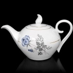 Porcelana Schmidt - Brasil(Fundada em 1945). Bule para chá em porcelana nacional, esmaltagem vítrea na cor branca, dotado de rica decoração com padrão de flores em estampagem, predominando as tonalidades azul, cinza e preto, realçado com frisos em douradura; bojo elipsóide, asa lateral em voluta, bico curvo revirado para fora, tampa ligeiramente abaulada encimada por pega com feitio de chama estilizada. Marca da manufatura ao fundo. Medidas: Alt.: 17 x Comp.: 29,5 x Larg.: 17,5 cm.
