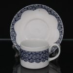 Xícara de chá em porcelana nacional, decoração em azul cobalto e branco com faixa contínua de volutas estilizadas, acompanhando o contorno recortado do pires. Marca da manufatura no verso. Medidas: Xícara: Alt.: 5,5 x Comp.: 10,5 x Larg.: 7,5 cm. ; Pires: Diam.: 15 cm.