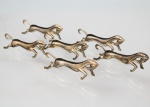 Conjunto com seis(06) descansos para talheres em metal prateado, representando cavalos em posição de salto, corpos estilizados com modelagem naturalista . Peças destinadas ao apoio de talheres em serviço de mesa. Apresenta marcas de uso. Medidas: Alt.: 3 x Comp.: 8,5 cm.