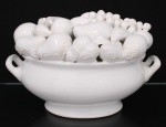 Centro de mesa em faiança vitrificada na tonalidade branca, modelado em formato de fruteira com composição de frutas em relevo, apresentando peras, uvas e maçãs, com alças laterais curvas e base oval.  Apresenta desgastes, perdas e craquelês no esmalte, conforme imagens. Medidas: Alt.: 24 x Comp.: 38 x Larg.: 27 cm.