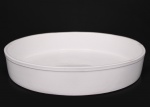 Travessa circular rasa em faiança branca, apresentando borda levemente espessada com friso relevado. Esmaltação branca uniforme com craquelê discreto decorrente do tempo. Medidas: Alt.: 7 x Diam.: 38,5 cm.