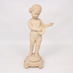 Escultura representando putto musicista executado em resina de tom marfim, retratado em pé sobre base circular elevada, executando instrumento de cordas do tipo bandolim. Assentada sobre plinto quadrangular com pés volutados e ornamentação floral em relevo. Trabalho de inspiração neoclássica, apresentando cabelos ondulados e panejamento parcial. Assinada na lateral da figura. Apresenta desgastes e pequenas marcas compatíveis com o material e a idade. Medidas: Alt.: 44,5 x Comp.: 16 x Larg.: 12 cm.