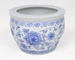 Cachepot em porcelana branca com decoração floral e folhagens em azul sob o esmalte, estilo "blue and white", ornamentado por frisos com motivos geométricos estilizados. Corpo de formato bojudo com borda larga e abertura circular. Medidas: Alt.: 18,5 x Diam.: 25 cm.