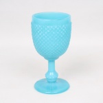 Taça executada em vidro opalinado, tonalidade azul turquesa, bojo preenchido por losangos moldados em relevo, padrão conhecido pelo senso comum como "bico de jaca", fuste tubular terminado em anel, assente sobre base circular. Medidas.: Alt.  17 x Diam. 8,5 cm. ;