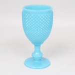 Taça executada em vidro opalinado, tonalidade azul turquesa, bojo preenchido por losangos moldados em relevo, padrão conhecido pelo senso comum como "bico de jaca", fuste tubular terminado em anel, assente sobre base circular. Med.: Alt. 15 x Diam. 8 cm.