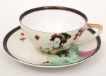 Xícara para chá em porcelana japonesa, bojo hemisférico com alça estilizada integrada. Decoração policromada representando figura feminina em trajes tradicionais japoneses, acompanhada por ramos de folhas estilizadas. Borda realçada por friso em tonalidade preta e contorno com filete dourado. Base marcada com inscrição Made in Japan. Medidas: Xícara: Alt.: 5 x Comp.: 12 x Larg.: 10 cm. ; Pires: Diam.: 15 cm.