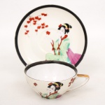 Xícara para chá em porcelana japonesa, bojo hemisférico com alça estilizada integrada. Decoração policromada representando figura feminina em trajes tradicionais japoneses, acompanhada por ramos de folhas estilizadas. Borda realçada por friso em tonalidade preta e contorno com filete dourado. Base marcada com inscrição Made in Japan. Medidas: Xícara: Alt.: 5 x Comp.: 12 x Larg.: 10 cm. ; Pires: Diam.: 15 cm.