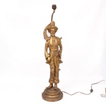 Luminária executada em resina patinada e dourada, representando figura masculina orientalista em trajes palacianos, portando cimitarra à cintura e turbante com pluma estilizada. Base circular escalonada, haste de sustentação posterior e braço elevado para soquete. Medidas: Alt.: 82 x Diam.:  20 cm.
