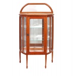 Vitrine expositora de pequenas dimensões, em madeira de lei com lâmina de mogno, estilo Art Nouveau (primeiras décadas do século XX), corpo de formato semicircular com laterais facetadas envidraçadas, porta frontal com vidro e fechadura, interior com prateleiras em vidro apoiadas em suportes metálicos, fundo espelhado, montantes delgados, tampo com placa em mármore encaixada e moldura com marchetaria em filetes, espaldar superior recortado com espelho integrado, assente sobre pernas afiladas de seção quadrangular com leve adelgaçamento e pés retos. Medidas: Alt.: 99 x Comp.: 59 x Larg.: 20 cm.