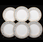 NORITAKE, Nagoya - Japão(Fundada em 1904 pelos irmãos Ichizaemon e Toyo Morimura). Exuberante conjunto de pratos rasos para jantar em porcelana da década de 1960/70, padrão POLONAISE (2045); esmaltagem vítrea na cor branca, aba profusamente ornamentada por composição vegetalista, composta por rinceau, volutas, ramos, folhas e flores dispostas em repetição, sobre cartela de tonalidade azul ciano, seguindo repertório derivado de padrões europeus, estilo neoclássico e revivalista; borda e caldeira circundadas generosa aplicação de filetes à ouro. Marca da manufatura no verso. Composto de seis(06) unidades. Medida: Diam.: 26,8 cm.