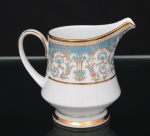NORITAKE, Nagoya - Japão(Fundada em 1904 pelos irmãos Ichizaemon e Toyo Morimura). Exuberante leiteira em porcelana da década de 1960/70, padrão POLONAISE (2045); bojo cônico assente sobre base circular, fusamente ornamentada por composição vegetalista, composta por rinceau, volutas, ramos, folhas e flores dispostas em repetição, sobre cartela de tonalidade azul turquesa, realçados por rica aplicação de douração, seguindo repertório derivado de padrões europeus, estilo neoclássico e revivalista; bordas contornadas com generosa aplicação de filetes à ouro e faixa perolada pontilhada, bico vertedor proeminente e alça lateral em voluta. Marca da manufatura no verso. Medidas: Alt.: 10 x Comp.: 12 x Larg.: 8 cm.