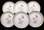Porcelana Real, Mauá - SP(Fundada em 1943 por Fritz Erwin Schmidt). Elegante conjunto de pratos rasos em porcelana nacional da década de 1950/60; esmaltagem vítrea na cor branca, orla circundada por faixa de acabamento nacarado, sobreposta por barrado contínuo de leques estilizados, guirlandas e frisos em douradura, centro dotado de bela composição botânica em estampagem policromada, predominando as tonalidades preta, rosa, azul e amarelo. Marca manufatura no verso. Composto de seis(06) unidades. Medida: Diam.: 25 cm.
