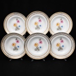 Porcelana Real, Mauá - SP(Fundada em 1943 por Fritz Erwin Schmidt). Elegante conjunto de pratos fundos porcelana nacional da década de 1950/60; esmaltagem vítrea na cor branca, orla circundada por faixa de acabamento nacarado, sobreposta por barrado contínuo de leques estilizados, guirlandas e frisos em douradura, centro dotado de bela composição botânica em estampagem policromada, predominando as tonalidades preta, rosa, azul e amarelo. Marca manufatura no verso. Composto de seis(06) unidades. Medida: Diam.: 23,5 cm.